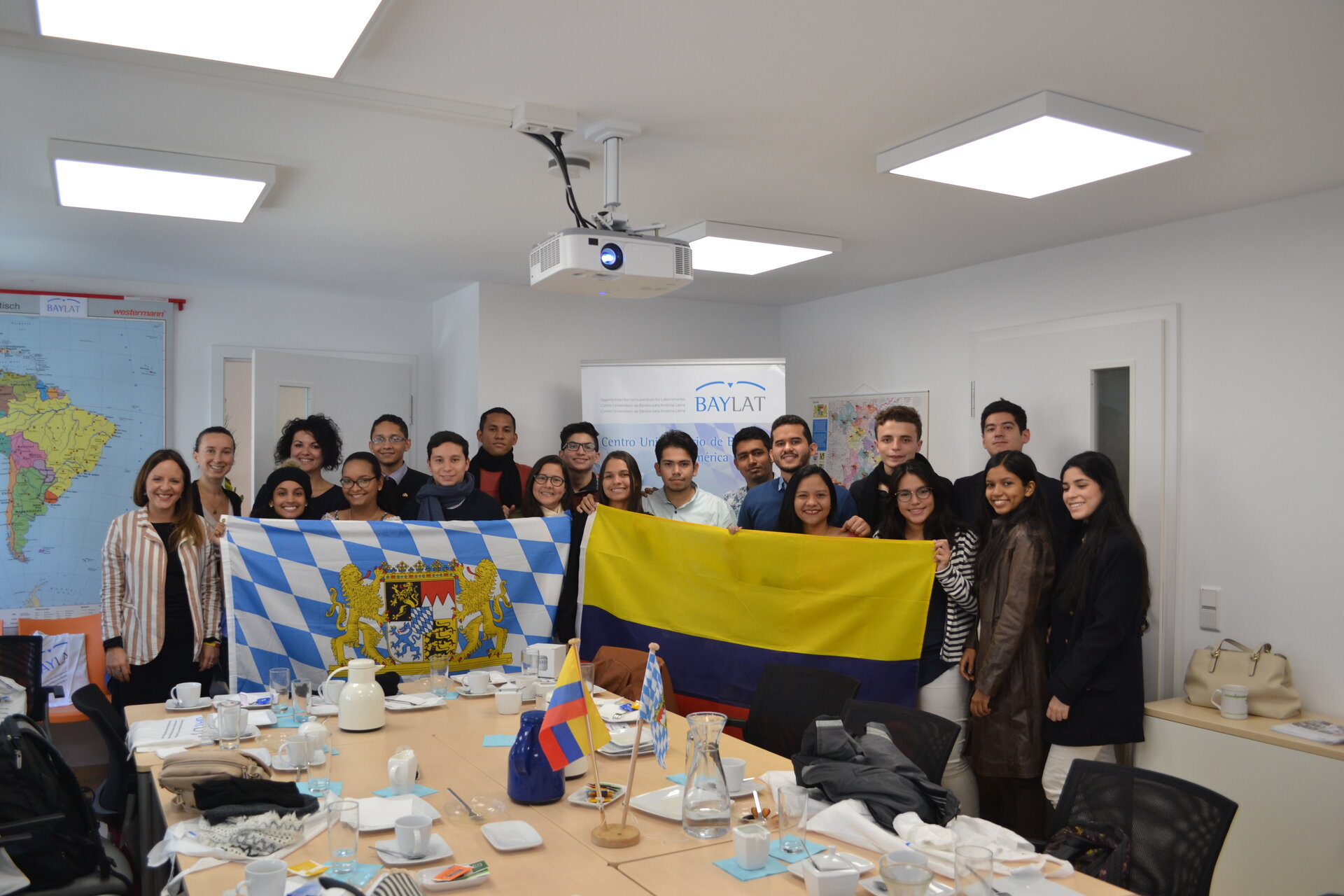 [Translate to Spanish:] Gruppenbild: Die Gruppe hält die bayrische und kolumbianische Flagge 
